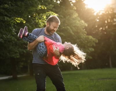 dad playing with daughter by swinging her around outside