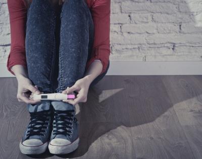 Person sitting on the ground holding a positive pregnancy test