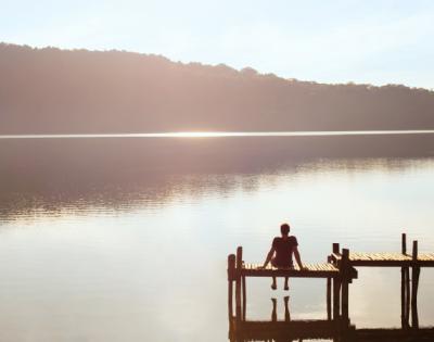 Person sitting on a dock overlooking a peaceful lake