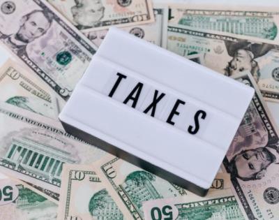 the word "taxes" on a marquee letterboard with money in the background