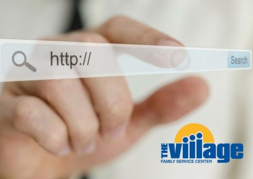 Woman's hand touching website address bar with Village logo