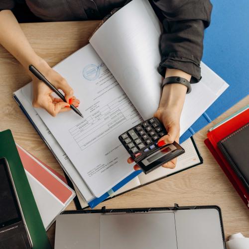 A person's hands hold a calculator and jot down numbers