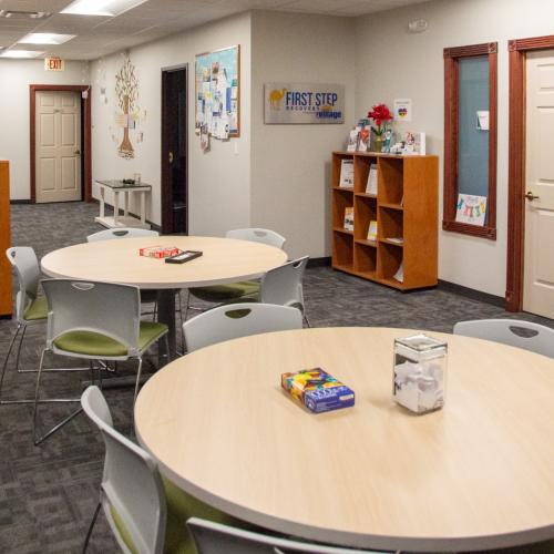First Step Recovery's space with bookshelves, resources, tables and chairs