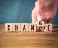Letter blocks spelling out chance with hand flipping the C to G so the word is changing to change